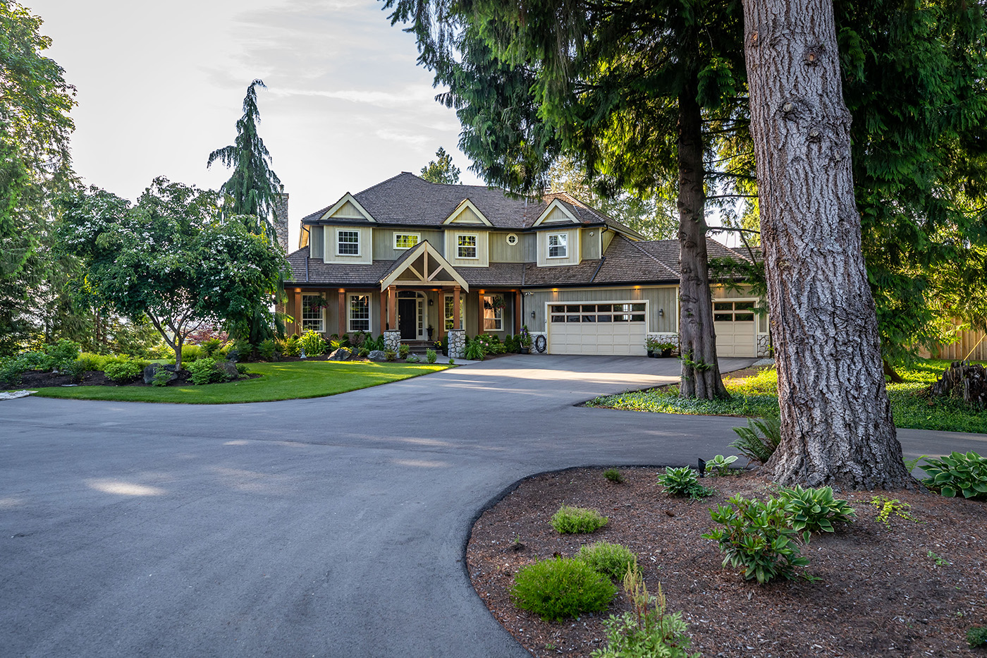 asphalt driveway with house and trees